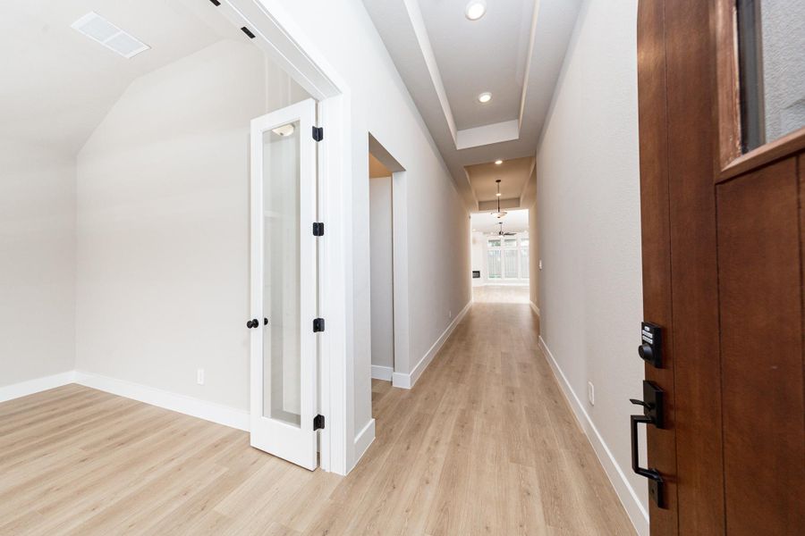 An inviting entrance opens up to an open-concept layout, seamlessly connecting the entry to the living areas with durable wood look tile flooring and striking architectural details.