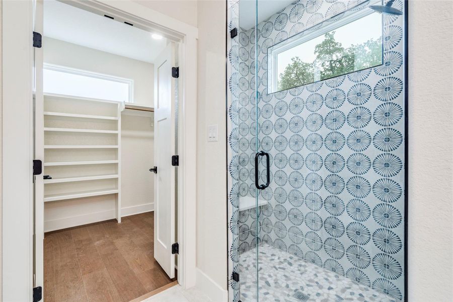 Bathroom featuring a walk in closet, a shower stall, and light wood finished floors