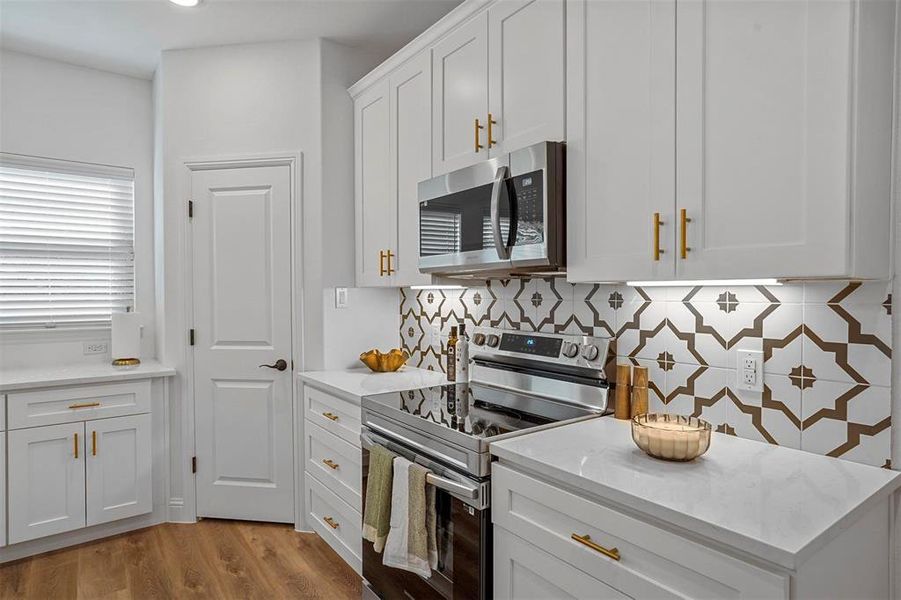 Kitchen featuring white cabinetry, light hardwood / wood-style floors, appliances with stainless steel finishes, and decorative backsplash