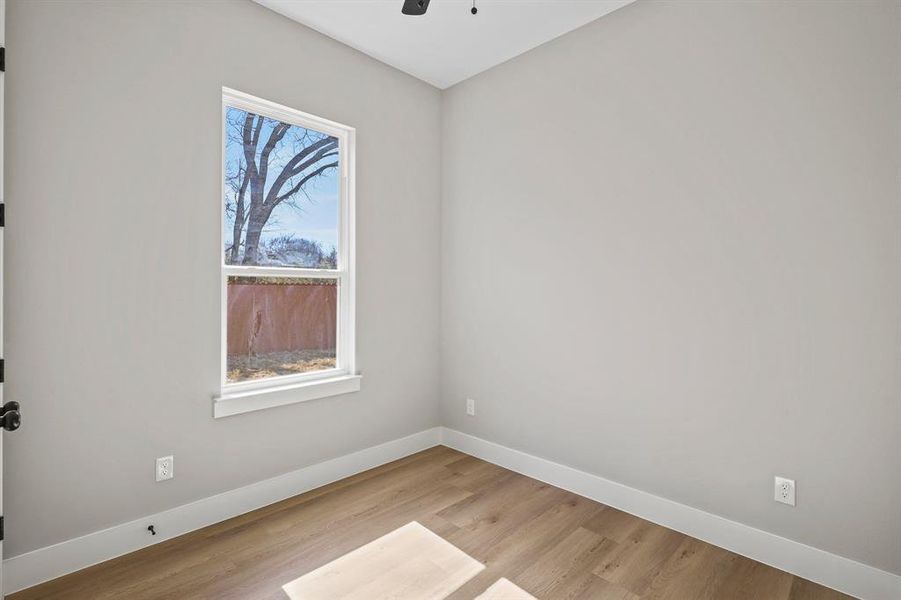 Spare room with baseboards, a ceiling fan, and light wood-style floors