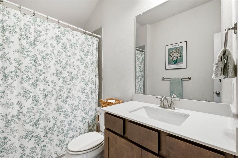 Full bathroom featuring a single vanity with wood-finish cabinetry, a white countertop, and an integrated sink