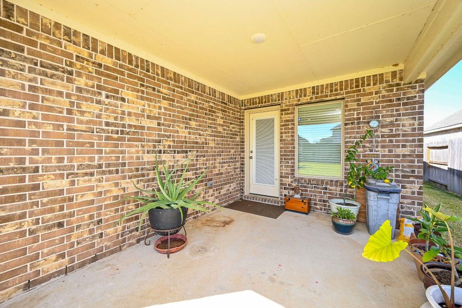 Cozy Covered Patio with Garden Accents & Brick Charm. Cozy Covered Patio with Garden Accents & Brick Charm.