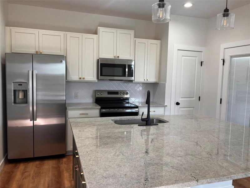 Kitchen featuring stainless steel appliances, light stone counters, tasteful backsplash, dark wood finished floors, and recessed lighting