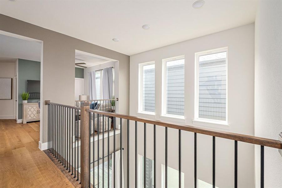 Corridor with an upstairs landing and light wood-style flooring