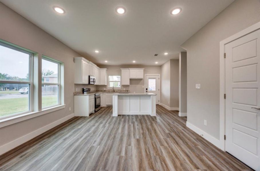 Kitchen with white cabinetry, light wood finished floors, stainless steel appliances, recessed lighting, and a kitchen island