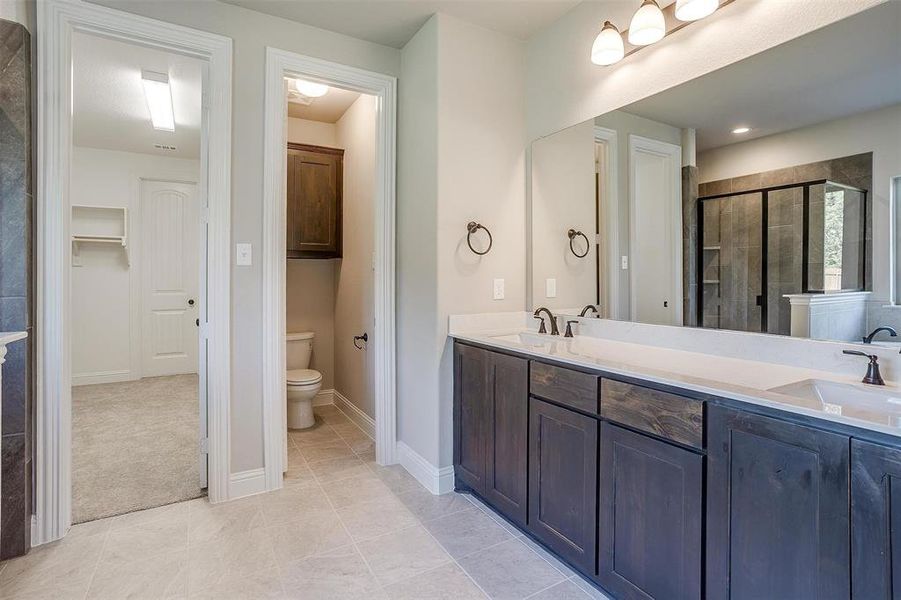 Bathroom with vanity, toilet, tile patterned floors, and an enclosed shower