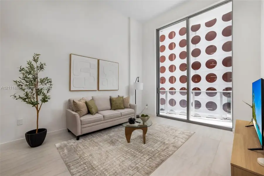 High-ceiling interior space featuring floor-to-ceiling glass paneling and light-toned tile flooring
