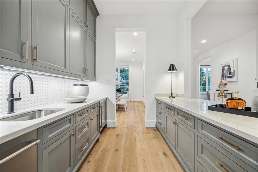 Bar features quartzite counters, stainless steel sink, kitchen aid ice maker, and beverage center