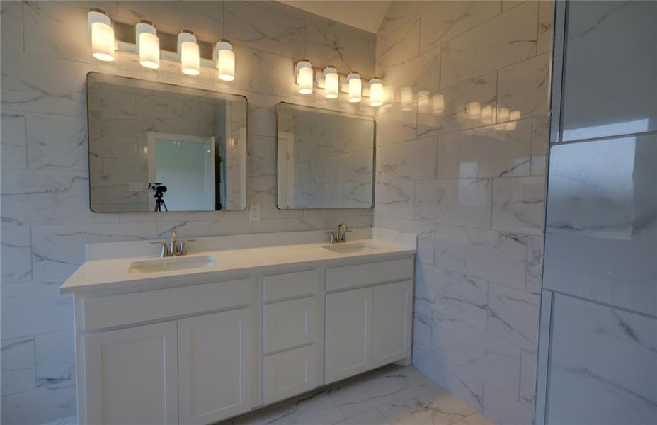Full bathroom with marble look tiles, double vanity, and tile walls Full bathroom with marble look tiles, double vanity, and tile walls