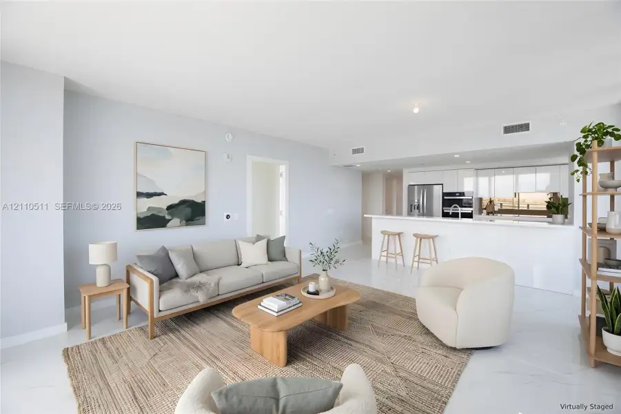 Open-concept living space featuring high-gloss tile flooring, white cabinetry, integrated stainless steel appliances, and a peninsula with solid-surface countertops