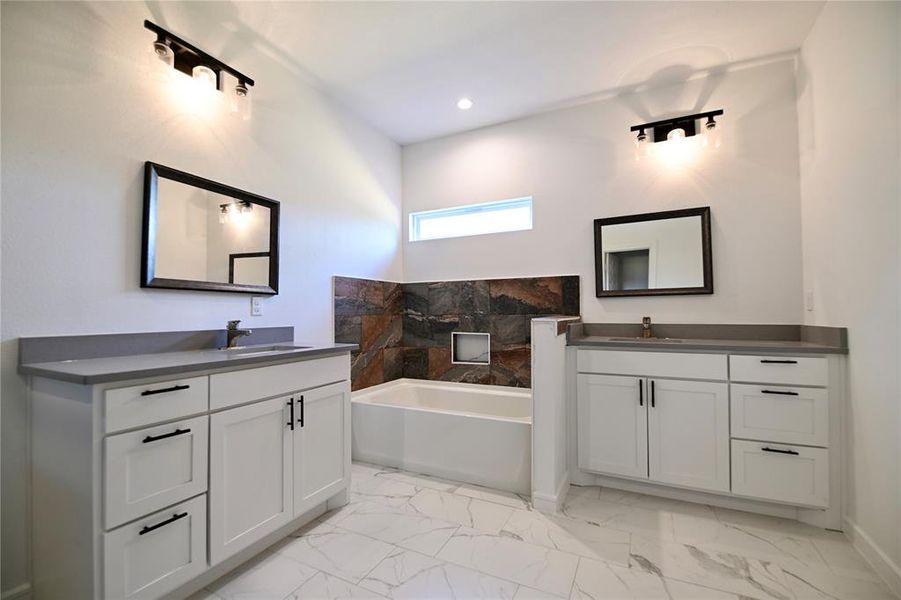 Bathroom with tile patterned flooring, a bathing tub, and vanity