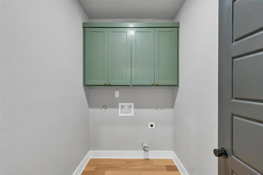 Washroom featuring light wood-style flooring, cabinet space, electric dryer hookup, gas dryer hookup, and washer hookup