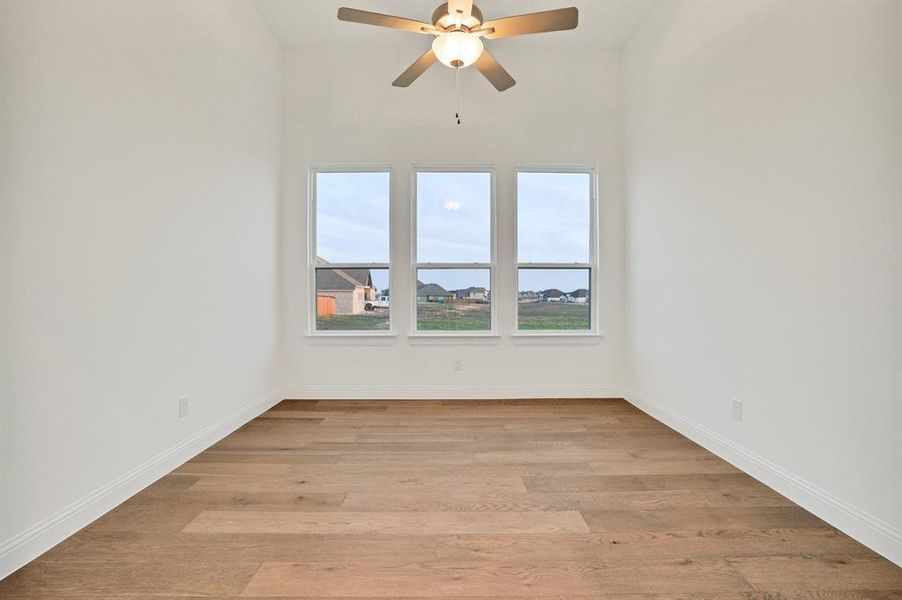 Study with light wood-type flooring and ceiling fan