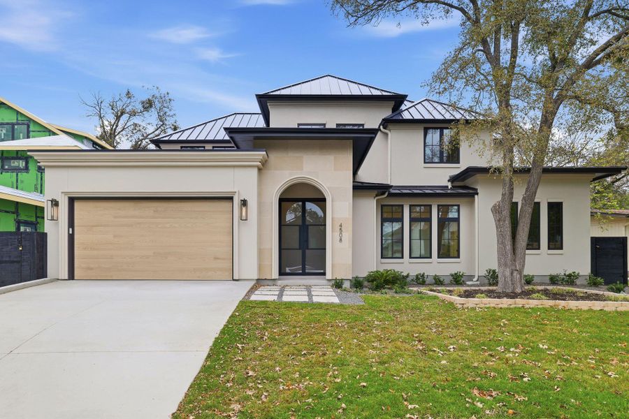 View of front of property with a standing seam roof, a metal roof, a front lawn, concrete driveway, and an attached garage