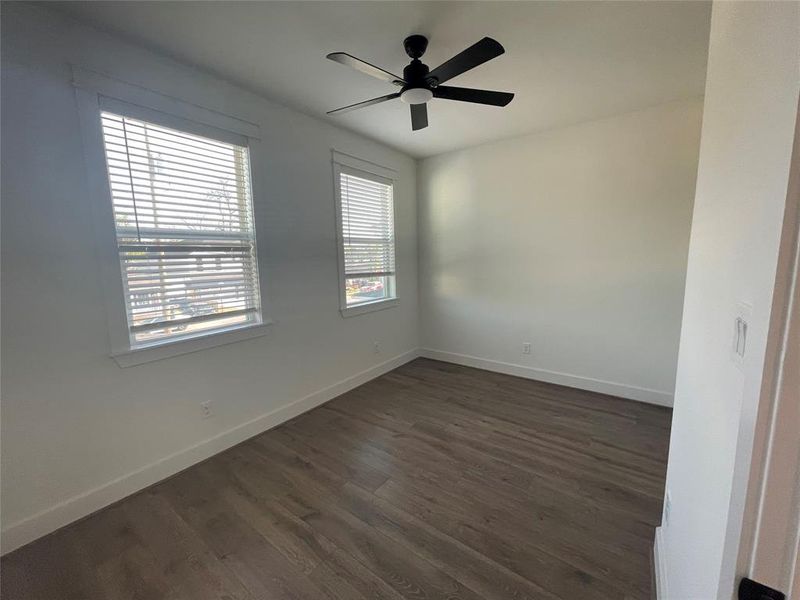 Empty room featuring a ceiling fan and dark wood-style floors