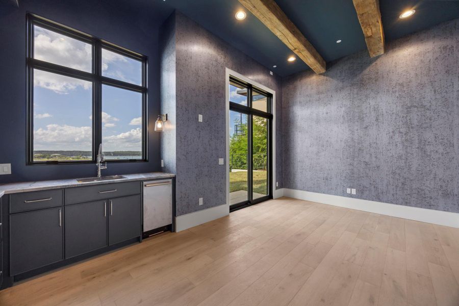 A refined living space with natural wood beams, wide plank hardwood floors, and a wet bar. A refined living space with natural wood beams, wide plank hardwood floors, and a wet bar.