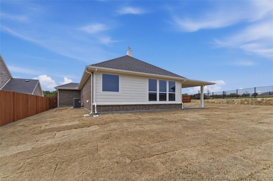 Back of house with a fenced backyard, brick siding, a chimney, and a patio
