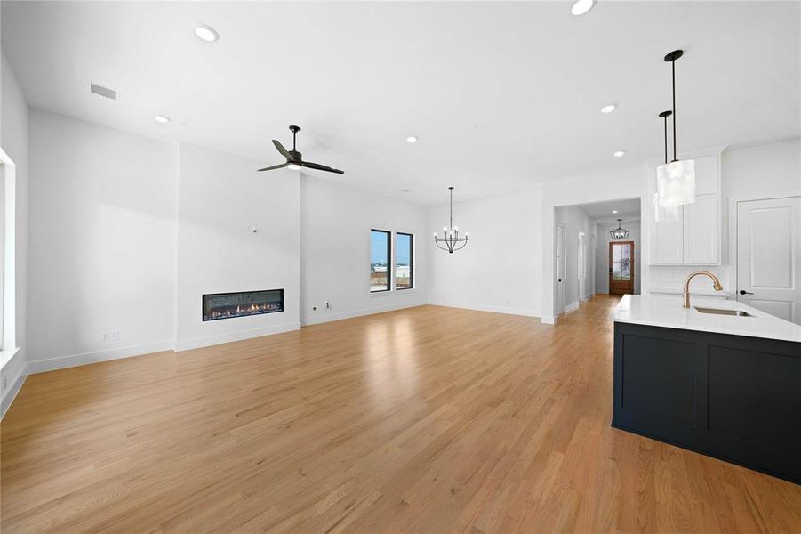 Unfurnished living room featuring ceiling fan, recessed lighting, a glass covered fireplace, and light wood-style flooring Unfurnished living room featuring ceiling fan, recessed lighting, a glass covered fireplace, and light wood-style flooring