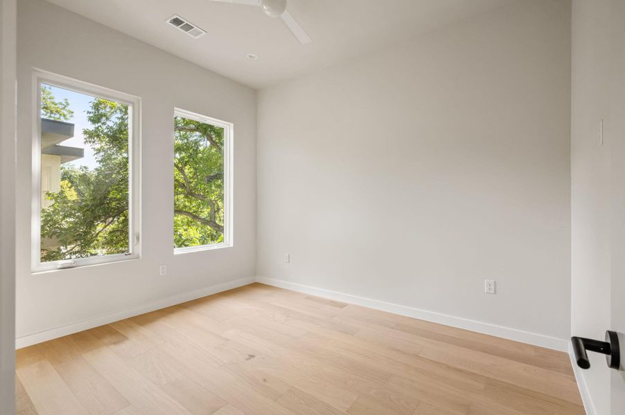 Generous windows frame leafy views, illuminating the clean lines and smooth hardwood flooring. Generous windows frame leafy views, illuminating the clean lines and smooth hardwood flooring.