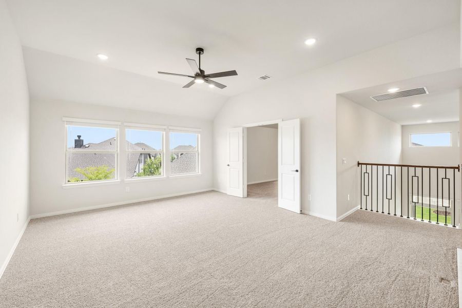 Spacious upstairs bonus room with vaulted ceiling, ceiling fan, carpet flooring, and open stair railing Spacious upstairs bonus room with vaulted ceiling, ceiling fan, carpet flooring, and open stair railing