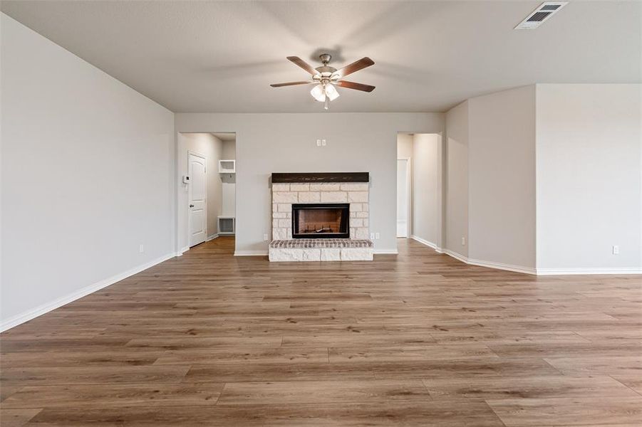 Unfurnished living room with a fireplace, a ceiling fan, and light wood-style flooring