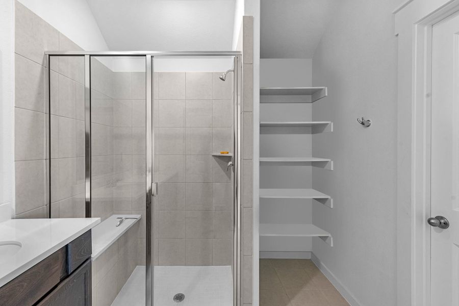 This additional view of your primary bathroom features a large walk in shower with added storage, and a large walk-in closet.