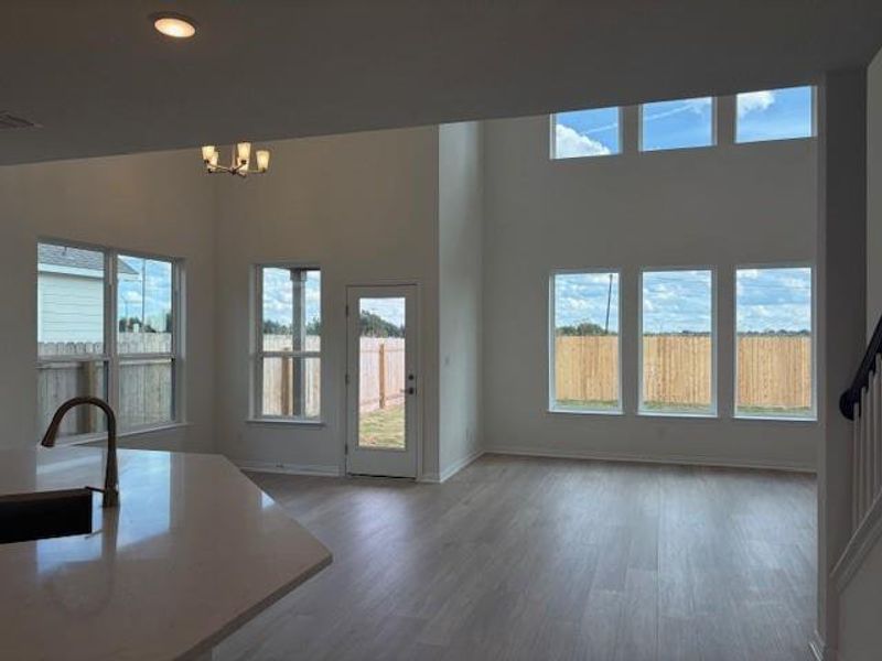Unfurnished living room featuring wood finished floors, a chandelier, recessed lighting, a high ceiling, and stairway Unfurnished living room featuring wood finished floors, a chandelier, recessed lighting, a high ceiling, and stairway