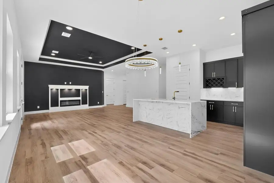 A well-lit, open-concept living area boasts a modern fireplace and a striking kitchen island.