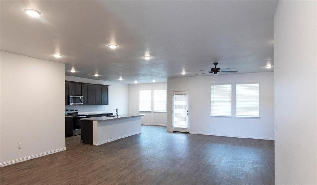 Kitchen featuring dark hardwood / wood-style flooring, stainless steel appliances, ceiling fan, sink, and a center island with sink