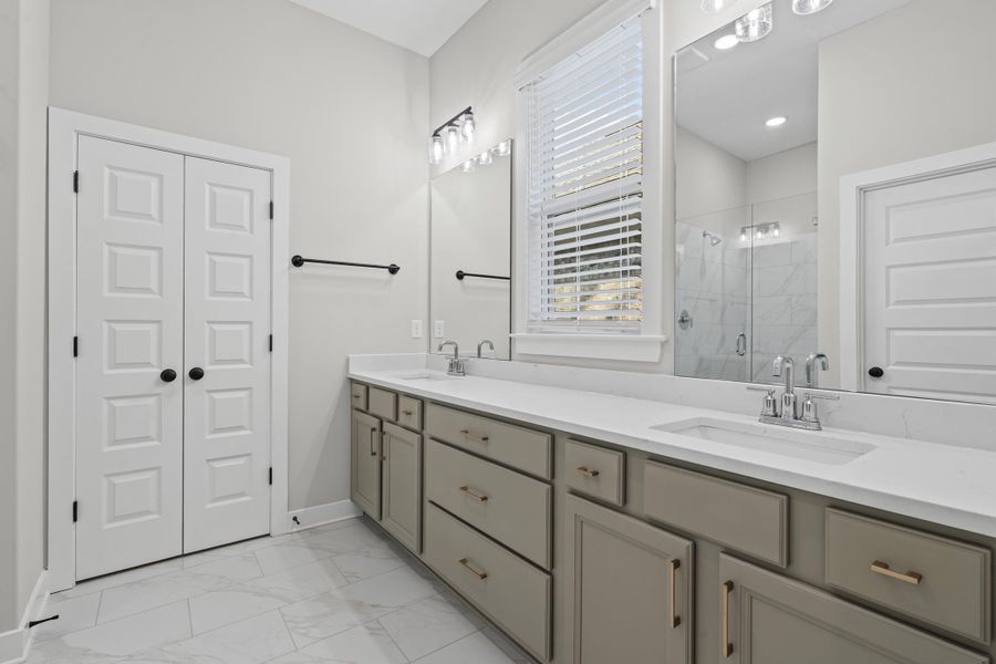 Full bathroom with a stall shower, light marble finish flooring, and double vanity