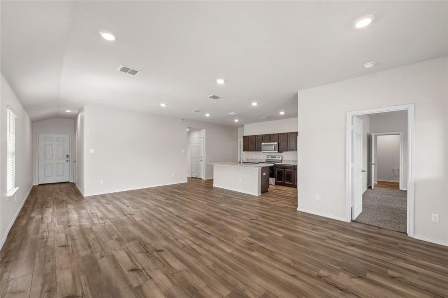 Unfurnished living room with dark wood-style flooring, recessed lighting, and vaulted ceiling Unfurnished living room with dark wood-style flooring, recessed lighting, and vaulted ceiling