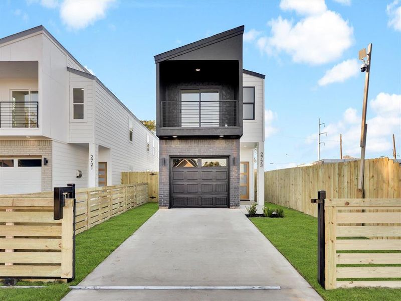 Modern home featuring a balcony, a front yard, and a garage