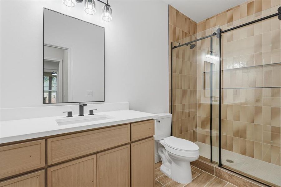 Bathroom featuring a light wood-finish vanity with a white countertop, an undermount sink, and a matte black faucet Bathroom featuring a light wood-finish vanity with a white countertop, an undermount sink, and a matte black faucet