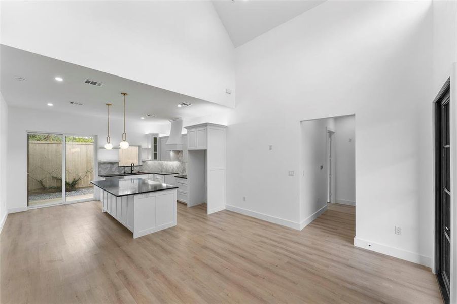Kitchen featuring white cabinets, a center island, dark countertops, open floor plan, and recessed lighting