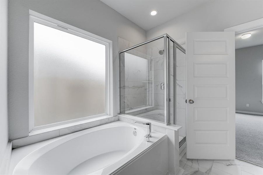 Experience luxury in this spa-like primary bathroom featuring a massive walk-in shower with tile surround. Sample photo of completed home with similar floor plan. As-built interior colors and selections may vary.