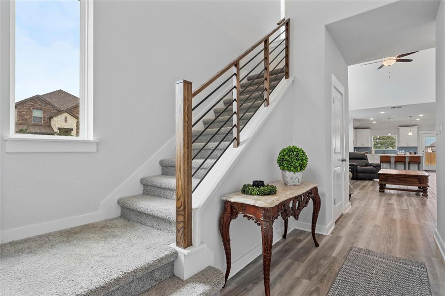 Stairway featuring baseboards, wood finished floors, ceiling fan, and a towering ceiling Stairway featuring baseboards, wood finished floors, ceiling fan, and a towering ceiling