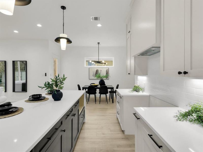 Kitchen with pendant lighting, gray cabinetry, light wood-type flooring, tasteful backsplash, and white cabinetry