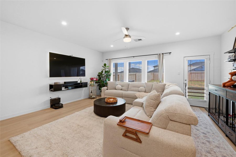 A different perspective reveals a bright and inviting living area with expansive windows, seamless backyard access through a glass door, and contemporary wood-style flooring. A different perspective reveals a bright and inviting living area with expansive windows, seamless backyard access through a glass door, and contemporary wood-style flooring.