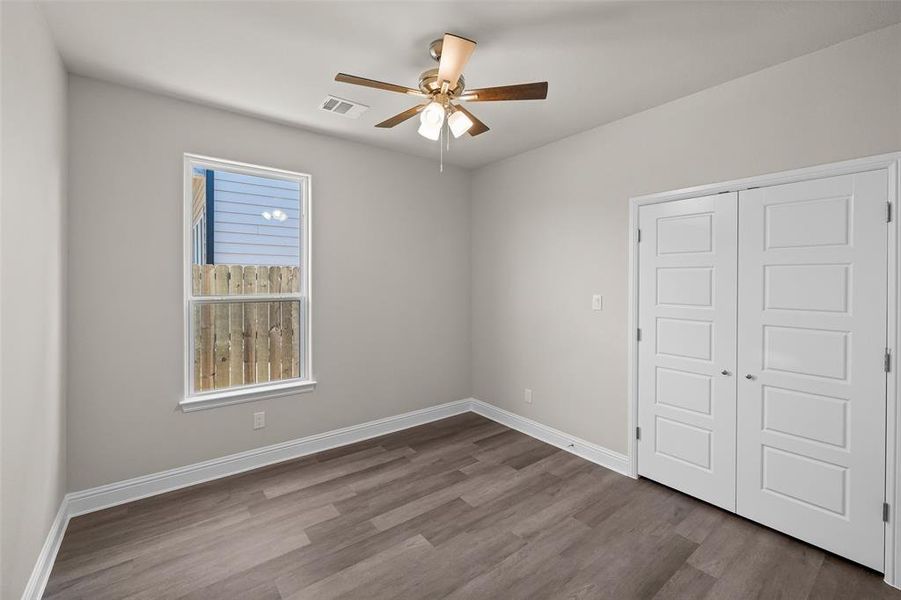 Unfurnished bedroom featuring dark hardwood / wood-style floors, a closet, and ceiling fan