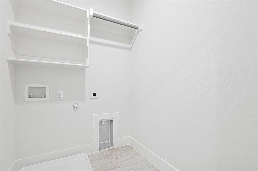 Utility room featuring shelving, a hanging rod, and tile flooring