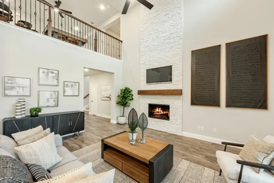 Two-story living room with stone fireplace, wood floors, and open loft overlooking the seating area below