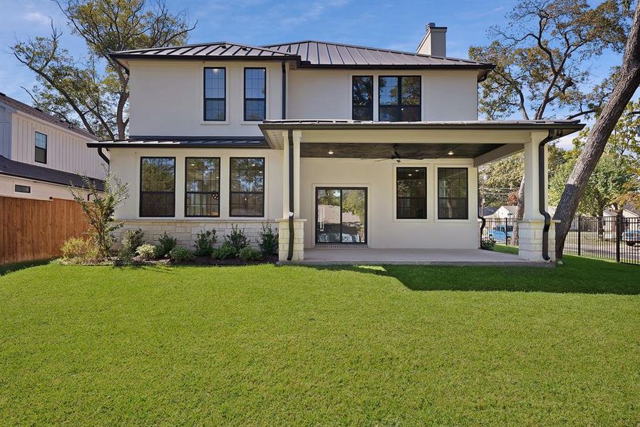 Back of house featuring stucco siding, a ceiling fan, a standing seam roof, and a metal roof Back of house featuring stucco siding, a ceiling fan, a standing seam roof, and a metal roof