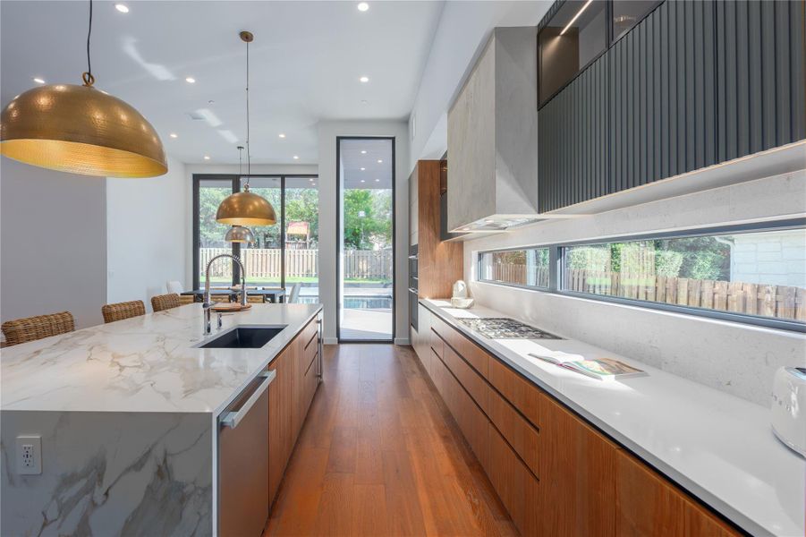 A sleek modern kitchen with lustrous hardwood floors and a spacious marble island, perfect for culinary endeavors.