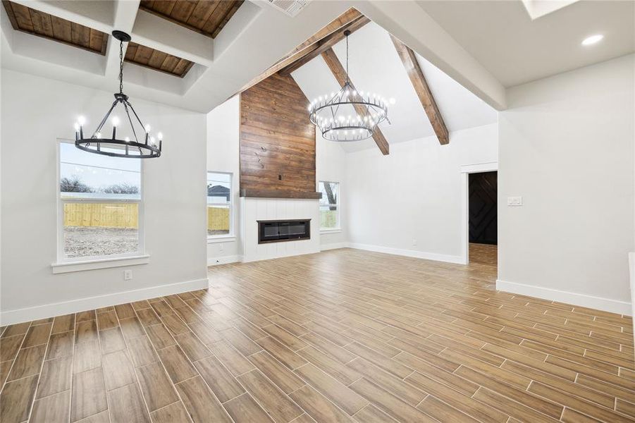 Unfurnished living room with beam ceiling, a notable chandelier, and a fireplace