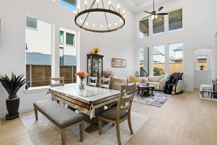 Dining area with light wood finished floors, a chandelier, ceiling fan, and a high ceiling Dining area with light wood finished floors, a chandelier, ceiling fan, and a high ceiling