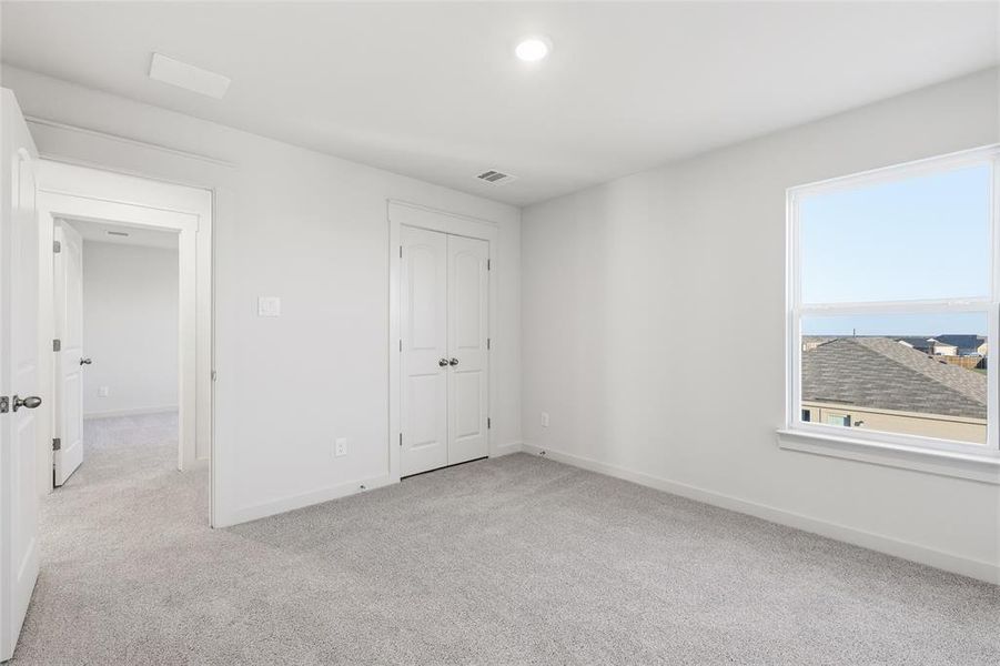 Carpeted interior room with a window, recessed lighting, and a bi-fold closet Carpeted interior room with a window, recessed lighting, and a bi-fold closet