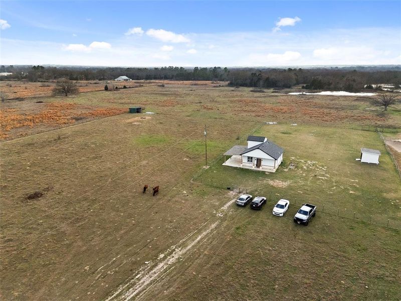 Expansive open acreage with a single-story residence featuring a covered porch Expansive open acreage with a single-story residence featuring a covered porch