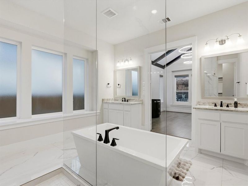 Freestanding soaking tub with matte black fixtures, set within a spacious walk-in shower featuring glass enclosure Freestanding soaking tub with matte black fixtures, set within a spacious walk-in shower featuring glass enclosure