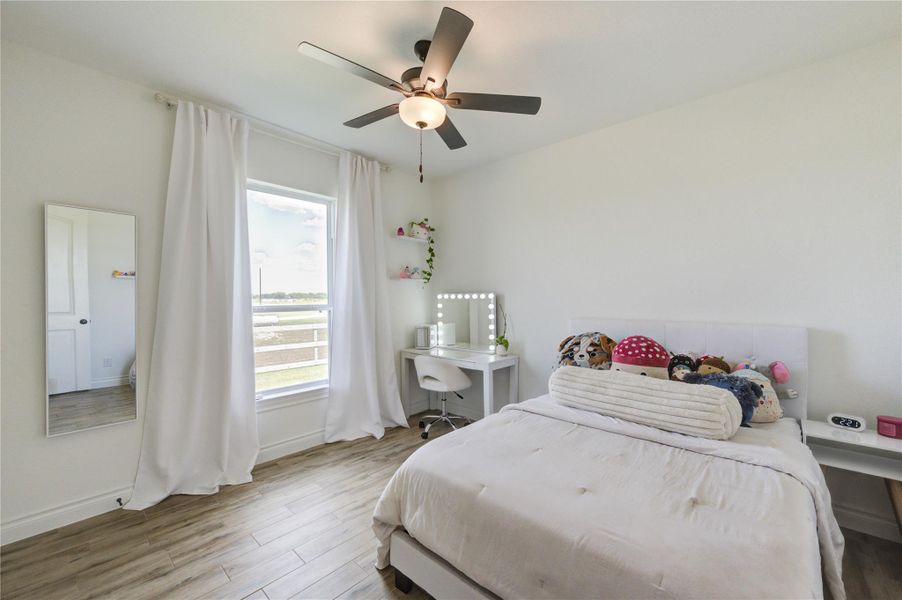 Bright and cozy bedroom featuring neutral tones, ceiling fan, and serene views of the property