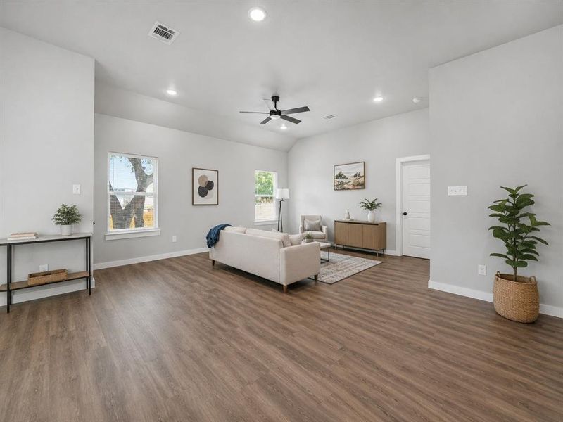Spacious living area featuring wood-finish flooring, recessed lighting, and a ceiling fan Spacious living area featuring wood-finish flooring, recessed lighting, and a ceiling fan